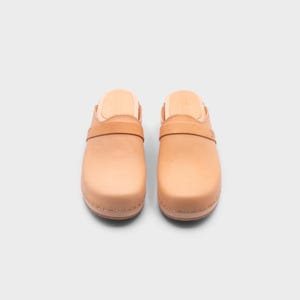 Malmö-style clogs designed by Sandgrens in classic Ecru Beige  leather. Featuring a smooth, slip-on design with a supportive strap for stability. The sturdy wooden sole and hand-stapled construction ensure durability and all-day comfort, making them a stylish and functional footwear choice.