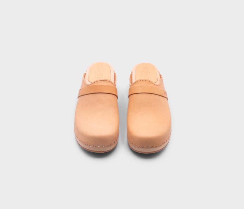 Malmö-style clogs designed by Sandgrens in classic Ecru Beige  leather. Featuring a smooth, slip-on design with a supportive strap for stability. The sturdy wooden sole and hand-stapled construction ensure durability and all-day comfort, making them a stylish and functional footwear choice.