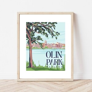 May include: A framed illustration of a park scene with a tree in the foreground, a lake, and a city skyline in the background. The text "OLIN PARK MADISON" is printed below the image.