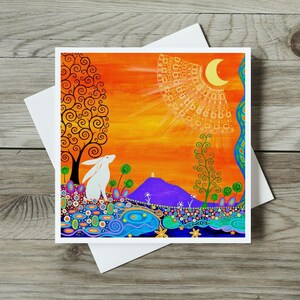 A square greetings card, featuring a white hare or rabbit looking towards a shiny crescent moon, with 2 Trees of Life and a purple Glastonbury Tor in the background. The card from an original painting is dominated by the shiny, glowing orange sky above a decorative Art Nouveau inspired meadow. This card can be personalised with a special message and sent directly to the receiver.