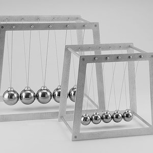 May include: Two silver Newton's cradle desk toys. The larger cradle has five balls and the smaller cradle has six balls.