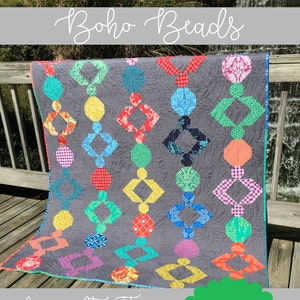 Może przedstawiać: Wzór kołdry o nazwie "Boho Beads" autorstwa Kelly Young. Kołdra prezentuje geometryczny wzór z kolorowymi koralikami w różnych kształtach i rozmiarach. Kołdra wykonana jest na szarym tle z kolorowych tkanin.