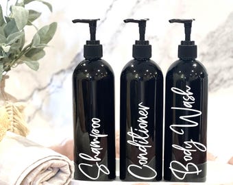 May include: Three black pump bottles with white labels. The labels read "Shampoo", "Conditioner", and "Body Wash".
