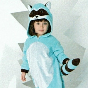 May include: A child wearing a blue and white raccoon onesie with a black and white striped tail. The onesie has a hood with raccoon ears and a face.