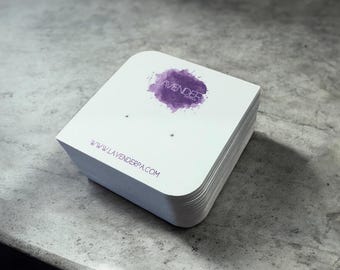 May include: A pile of white earring display cards with curved edges. Each card has a purple watercolour splash with the word "LAVENDER" and the website address www.lavenderpa.com printed in purple.