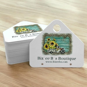 May include: A stack of white, house-shaped tags with a sunflower and truck design. The tags have a hole at the top and the text "Biz'ee B's Boutique" and "www.bizeebs.com". The design features sunflowers in a truck bed.