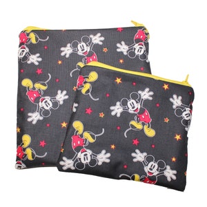 May include: Two zippered pouches with a black background and a repeating pattern of Mickey Mouse in red, yellow, and white. The pouches have yellow zippers.