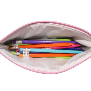 May include: A pink zippered pencil case filled with colorful pencils. The pencils are various colors, including purple, orange, blue, and green. The pencils have silver metal ends and the text "STAPLES No. 2" printed on them.