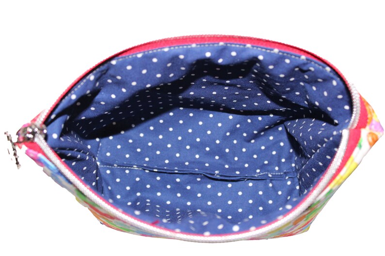 May include: A red zippered pouch with a white polka dot lining. The pouch is made of a colorful fabric with a floral pattern.