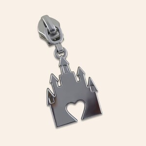 May include: Silver zipper pull with a castle design featuring a heart cutout.