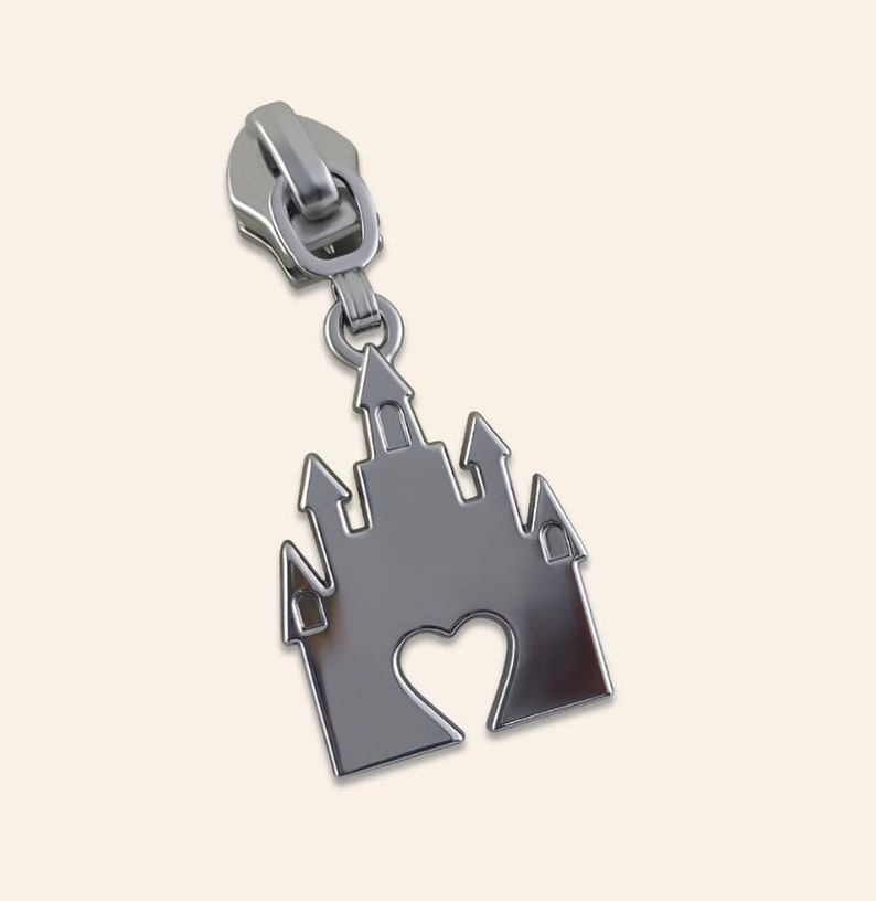 May include: Silver zipper pull with a castle design featuring a heart cutout.