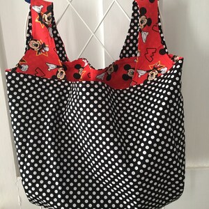 May include: A black and white polka dot reusable shopping bag with red and white Mickey Mouse fabric on the straps.