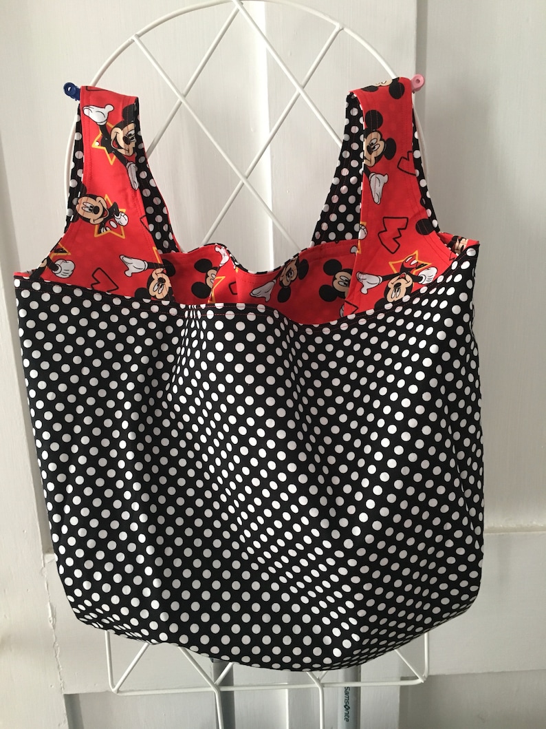 May include: A black and white polka dot reusable shopping bag with red and white Mickey Mouse fabric on the straps.