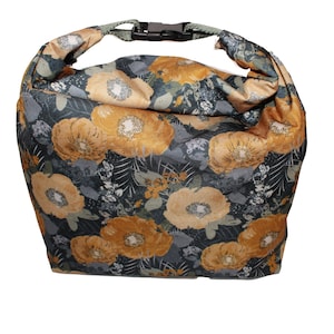Puede incluir: Una bolsa de almuerzo reutilizable con un estampado floral con flores amarillas y grises. La bolsa tiene un cierre de hebilla negro.