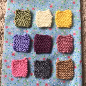 May include: Nine small knitted squares in various colors, including green, white, yellow, purple, maroon, pink, light pink, gray, and brown.