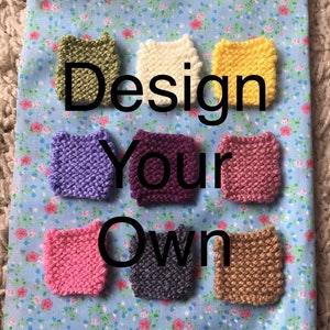 May include: Eight small knitted squares in different colors, including purple, pink, yellow, green, white, brown, and gray. The squares are arranged in a semi-circle on a blue and white floral fabric. The text "Design Your Own" is written in black letters above the squares.