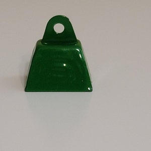 May include: A small, green metal bell with a loop on top. The bell is approximately 2.5 cm in diameter.