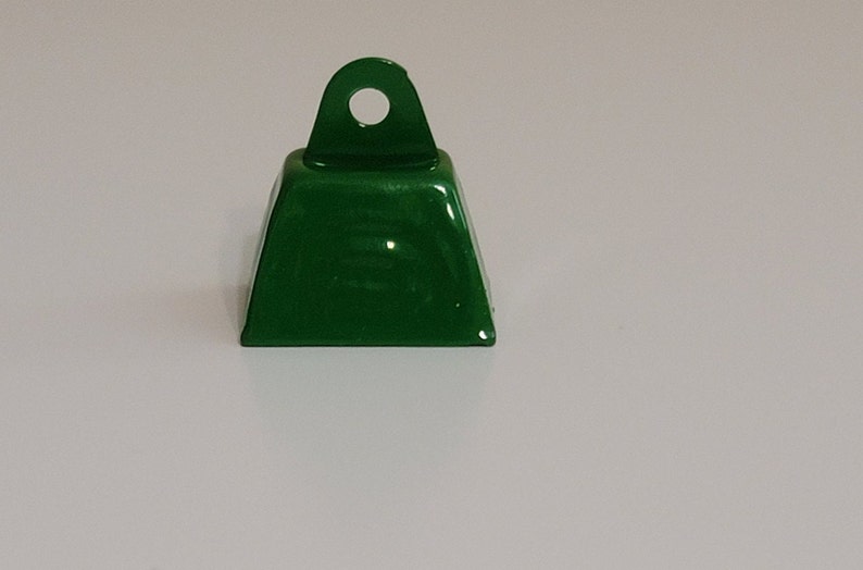 May include: A small, green metal bell with a loop on top. The bell is approximately 2.5 cm in diameter.