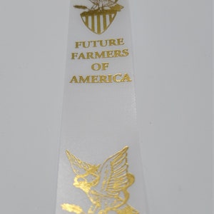 May include: White satin ribbon with gold foil print of an eagle and the words "Future Farmers of America".