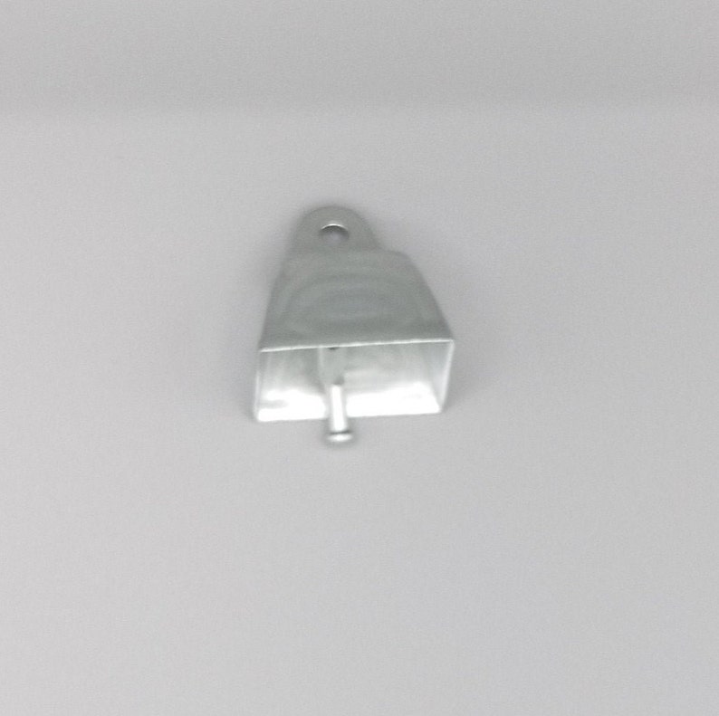 May include: A silver cowbell with a small, round hole at the top and a metal clapper inside.