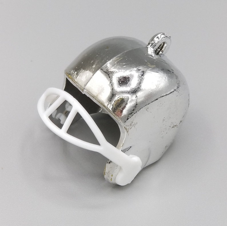 Peut inclure: Un casque de football am&eacute;ricain argent&eacute; avec une visi&egrave;re blanche. Le casque a une finition brillante et une petite boucle sur le dessus.