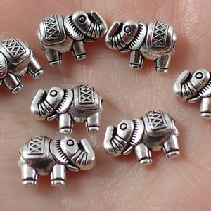 May include: Eight silver elephant charm beads. The beads are detailed with intricate patterns and have a slightly aged finish.