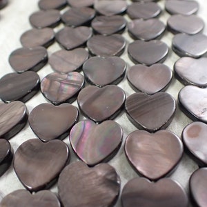 May include: A strand of dark brown heart-shaped shell beads. The beads have a slight iridescent sheen.