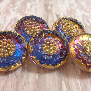 May include: Five iridescent glass buttons with a gold rim and a raised floral design in the centre. The buttons are blue, purple, and gold.