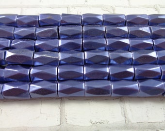 May include: A close-up of a strand of dark blue faceted glass beads. The beads are rectangular in shape and have a metallic sheen.