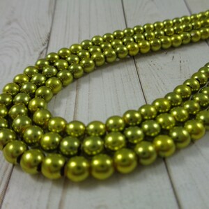 May include: A strand of shiny, lime green round beads. The beads are strung on a clear thread and are arranged in a circular pattern.