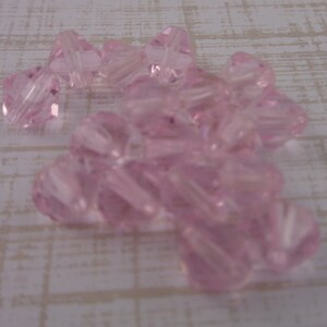 Puede incluir: Un mont&oacute;n de cuentas de vidrio rosa con un dise&ntilde;o facetado en forma de estrella.