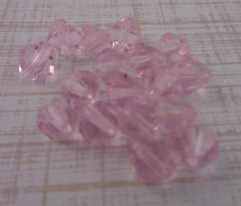 Puede incluir: Un mont&oacute;n de cuentas de vidrio rosa con un dise&ntilde;o facetado en forma de estrella.