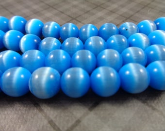 May include: A strand of light blue cat's eye beads. The beads are round and have a smooth, polished finish.