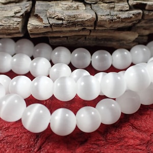 May include: A strand of white cat's eye beads. The beads are round and smooth, with a subtle shimmer.