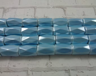 May include: A close-up of a strand of light blue faceted glass beads. The beads are rectangular in shape and have a smooth, shiny finish.