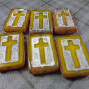 May include: Six yellow glass tiles with a white cross design. The tiles are rectangular and have a slightly textured surface.