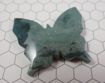 May include: A green and brown butterfly shaped stone carving. The stone has a mottled appearance and is polished.
