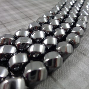 May include: A strand of shiny, silver-toned, faceted gemstone beads. The beads are round and have a smooth, polished finish.