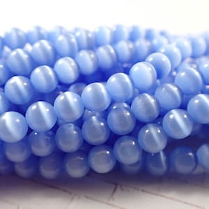 May include: A strand of light blue cat's eye beads. The beads are round and have a smooth, polished finish.