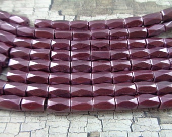 May include: A strand of dark purple faceted glass beads. The beads are rectangular in shape and have a glossy finish.