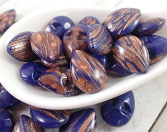 May include: A collection of blue and gold glass beads with a swirled pattern. The beads are shaped like teardrops and have a metallic finish.