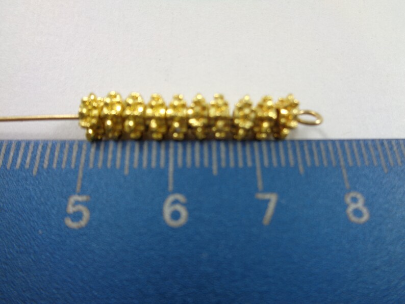 May include: A gold-colored metal bead chain with a loop at the end, measuring approximately 1 inch in length. The chain is made of small, round beads that are clustered together.