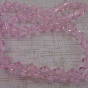 Puede incluir: Una hebra de cuentas de cristal rosa. Las cuentas son facetadas y tienen forma de diamante.