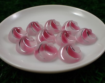 May include: A plate of pink and silver jelly candies with a swirl design.