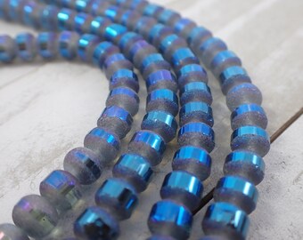 May include: A strand of iridescent blue glass beads with a frosted finish. The beads are round and have a metallic sheen.