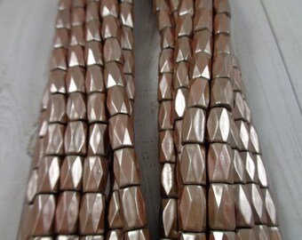 May include: A strand of faceted, metallic gold beads. The beads are shaped like small, elongated hexagons.