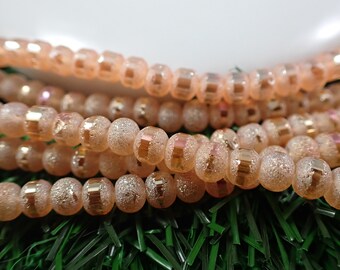 May include: A strand of peach-colored glass beads with a glittery finish and a metallic gold stripe around each bead.