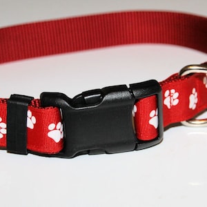 May include: Red dog collar with white paw prints and a black plastic buckle.