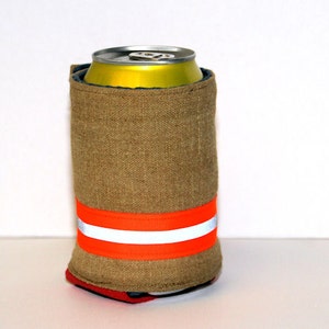 May include: A brown fabric can cooler with a bright orange and white reflective stripe. The cooler is holding a yellow aluminium can.