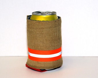 May include: A brown fabric can cooler with a bright orange and white reflective stripe. The cooler is holding a yellow aluminum can.